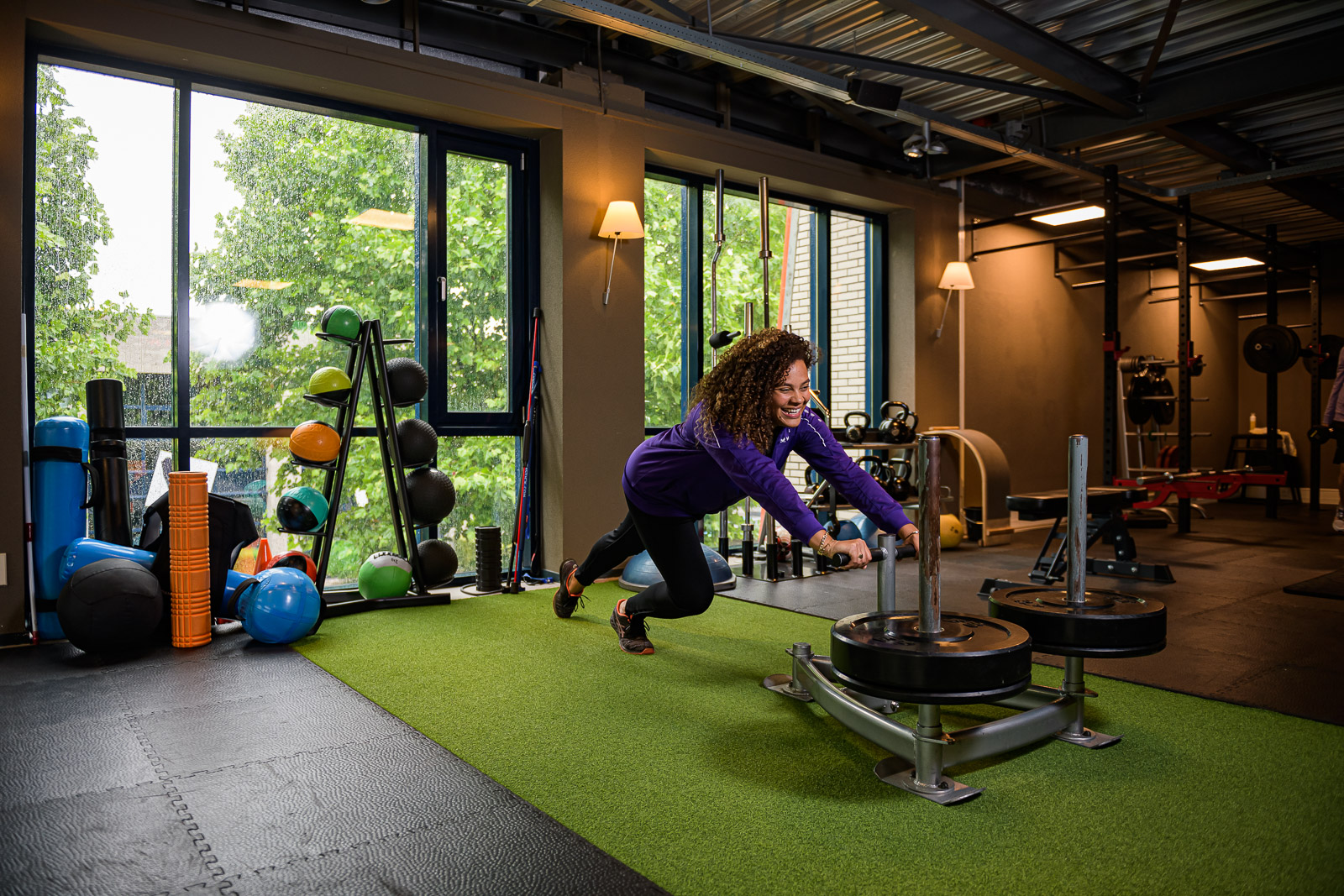 Vrouw duwt een power sled op een groene mat